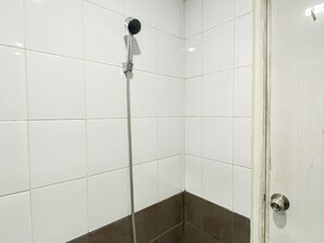 A shower with a handheld showerhead and a wall-mounted faucet, tiled walls, and a door with a metallic handle. - Nice Homey 2Br At Apartment Green Pramuka City (Jakarta)