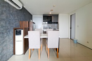 Une cuisine moderne avec un mur recouvert de carreaux, un four encastré et un coin repas comprenant une table et des chaises blanches.