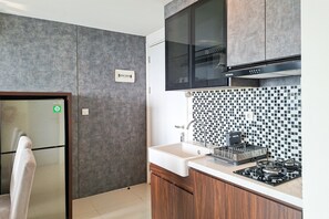 A modern kitchen with a built-in stove, a sink, and a microwave. - Bright And Convenient 2Br At Apartment Tuscany Residence (Tangerang)