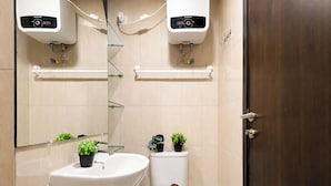 Et badeværelse med en hvid vask, toilet og to vægmonterede varmeapparater.