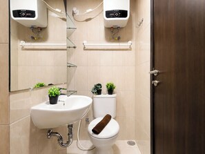 Un baño con un lavamanos blanco, un inodoro y dos calentadores de pared.