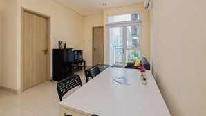 A modern apartment with a dining area, a kitchenette, and a large window providing a view of the city. - Bright Minimalist 2Br At Apartment Elpis Residence (Jakarta)