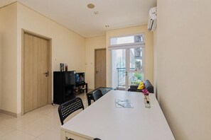 A modern apartment with a dining area, a kitchenette, and a large window providing a view of the city. - Bright Minimalist 2Br At Apartment Elpis Residence (Jakarta)