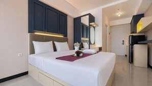 Ein Hotelzimmer mit einem großen Bett, einem Nachttisch, einem Spiegel, einem Kleiderschrank und einer Küchenzeile.