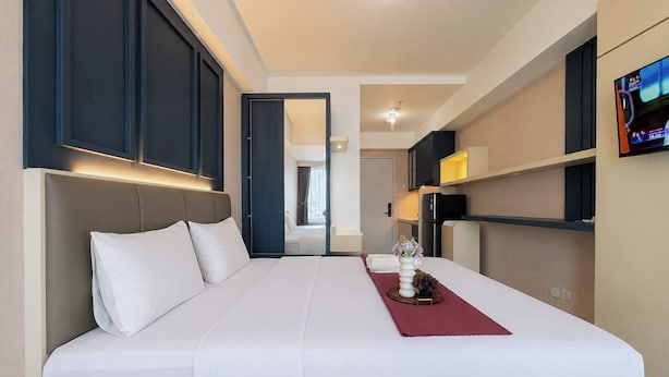 Ein Hotelzimmer mit einem großen Bett, einem an der Wand befestigten Fernseher und einer Tür zu einem Badezimmer.