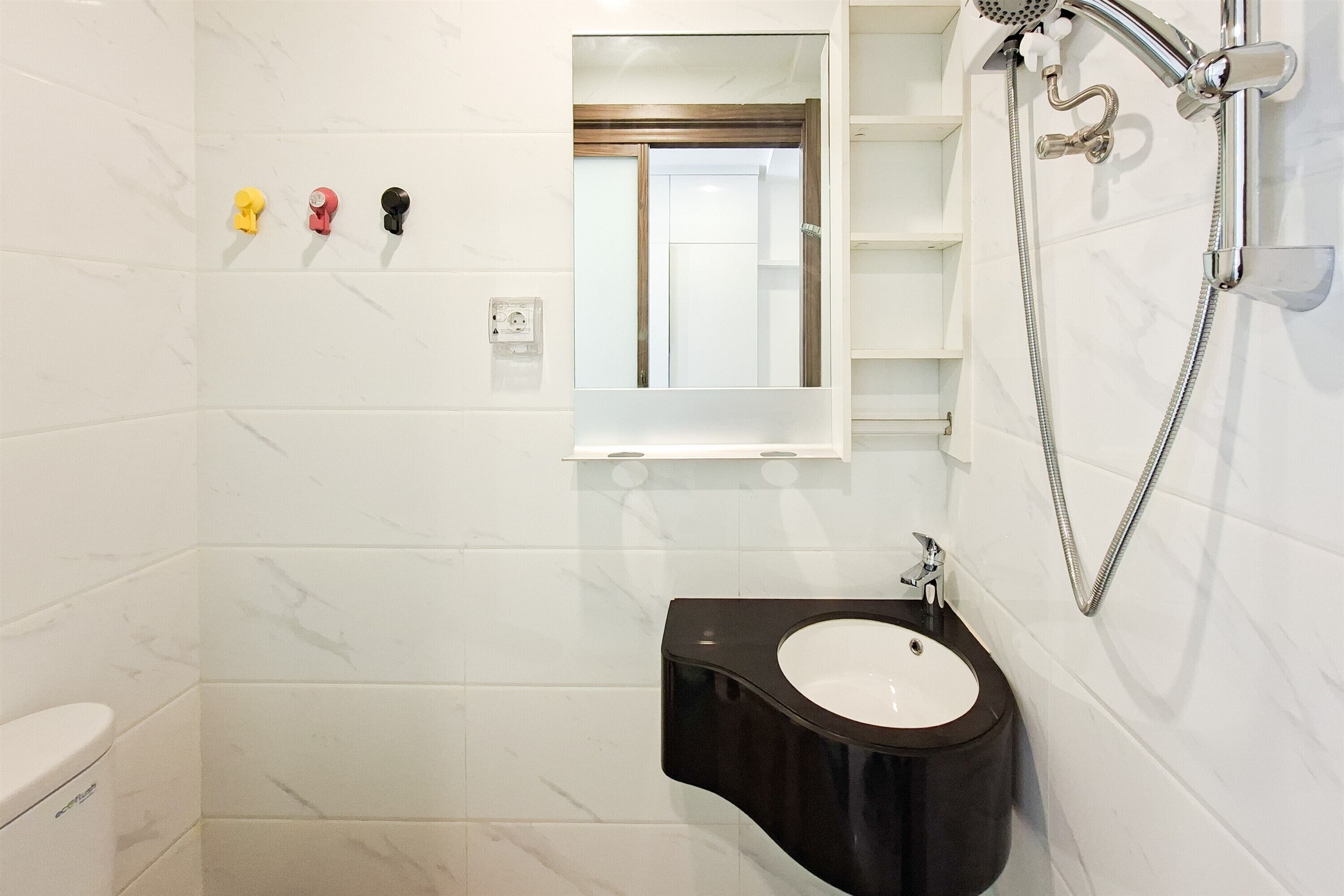 A bathroom with a white tiled wall, a black sink, a mirror, and a shower.