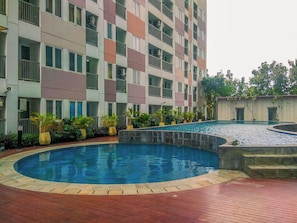A multi-story residential building with balconies, a swimming pool, and potted plants. - Best Deal Studio Apartment At Grand Sentraland Karawang (Karawang)