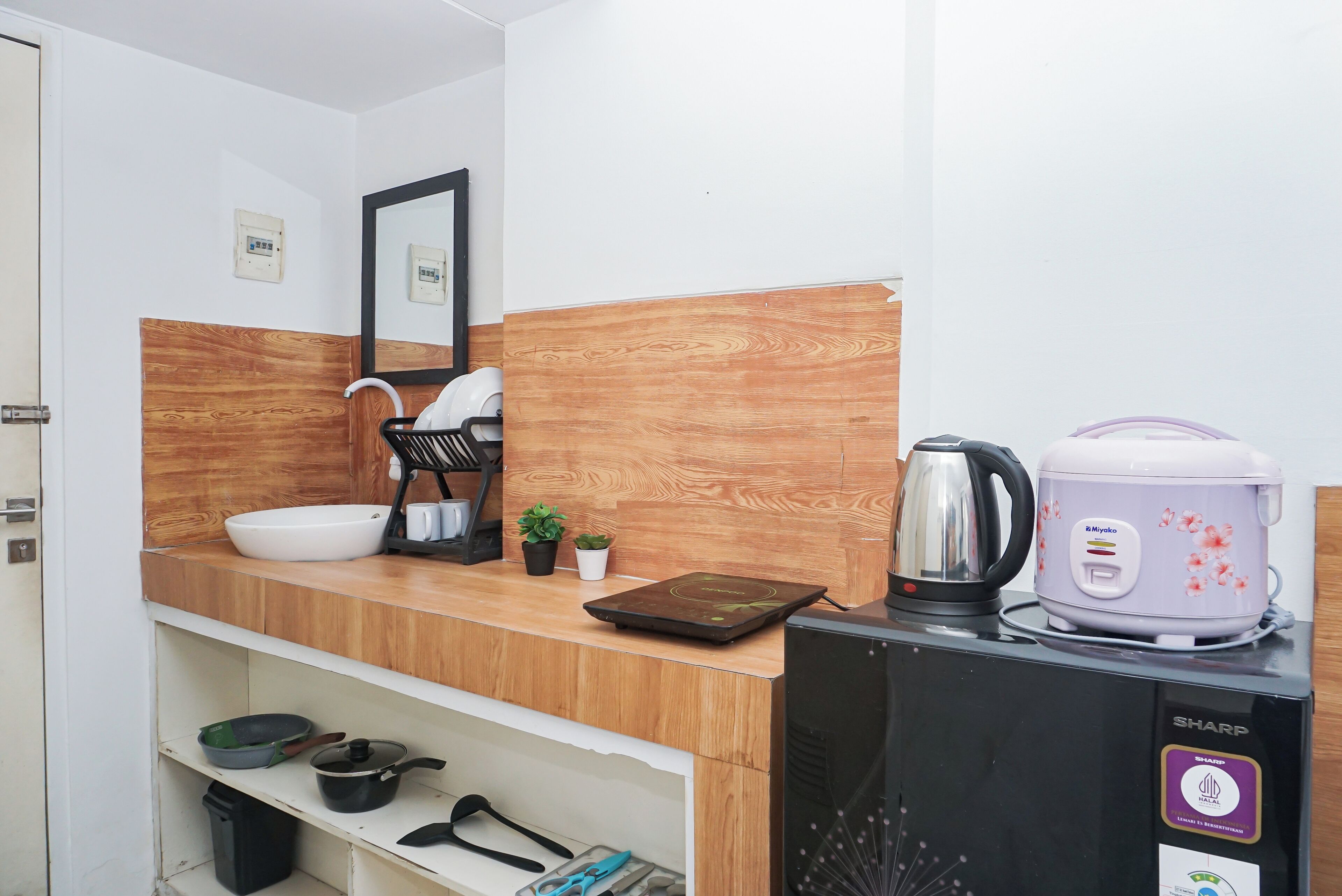 Una kitchenette equipada con una cocedora de arroz, un hervidor y una pequeña planta en maceta.