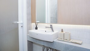 Casa de banho com lavatório branco, espelho e porta-toalhas.