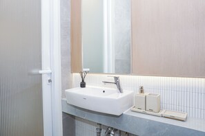 A bathroom with a white sink, a mirror, and a towel rack. - Charming Modern Studio At Apartment Mustika Golf Residence (Cikarang)