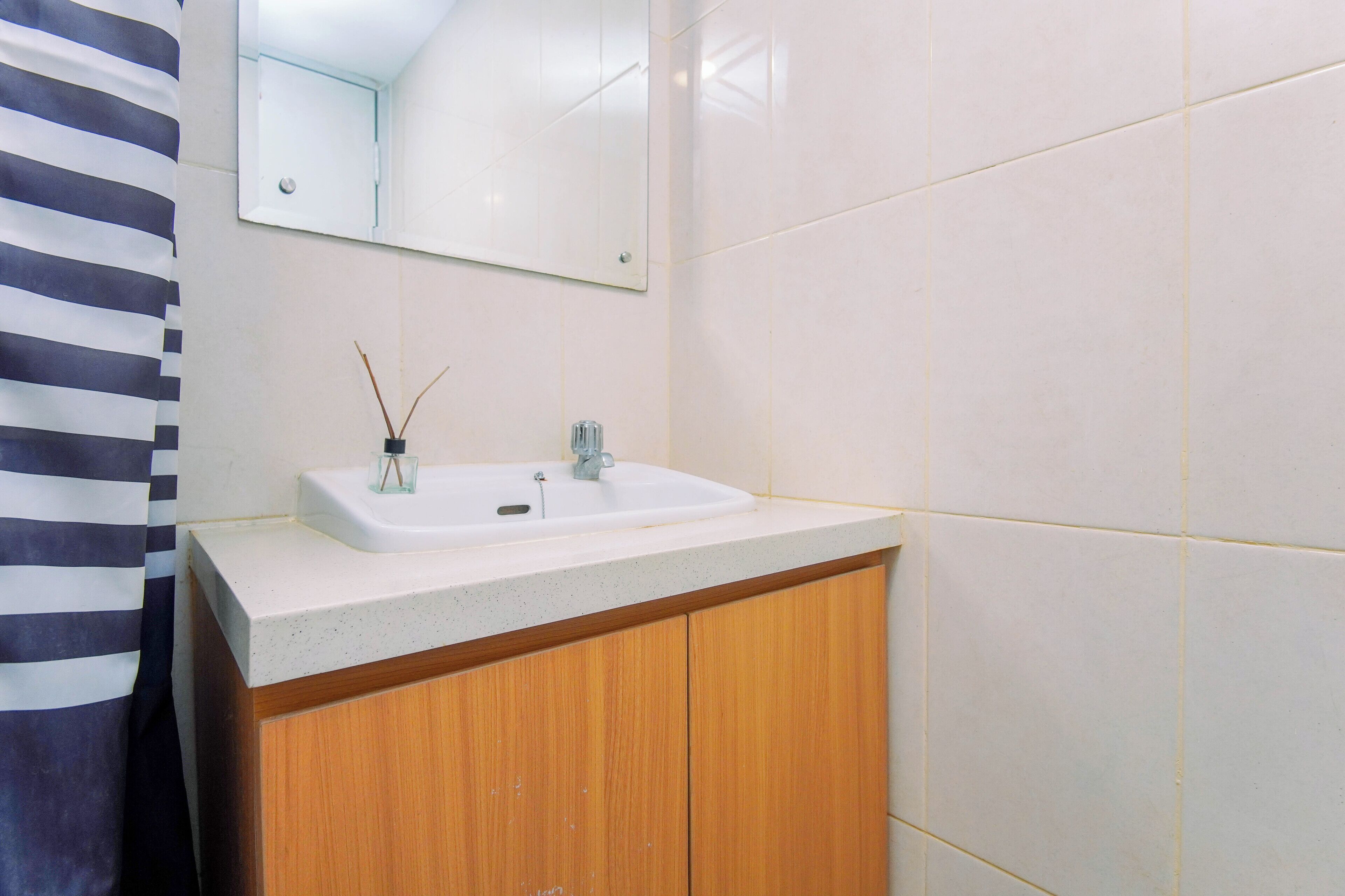 Un baño con un lavabo blanco, un mueble de madera y un espejo sobre el lavabo.