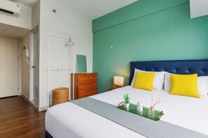 Une chambre d’hôtel avec un lit, une table de chevet, une lampe et une petite plante posée sur la table de chevet.