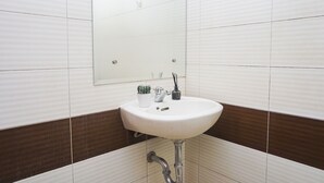 A bathroom with a white sink, a mirror, and a potted plant. - Compact Minimalist Studio At Apartment Margonda Residence 3 (Depok)