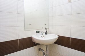 A bathroom with a white sink, a mirror, and a potted plant. - Compact Minimalist Studio At Apartment Margonda Residence 3 (Depok)