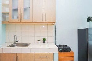 Una cocina con armarios de madera, un lavamanos de acero inoxidable, una estufa a gas y dos plantas en macetas.