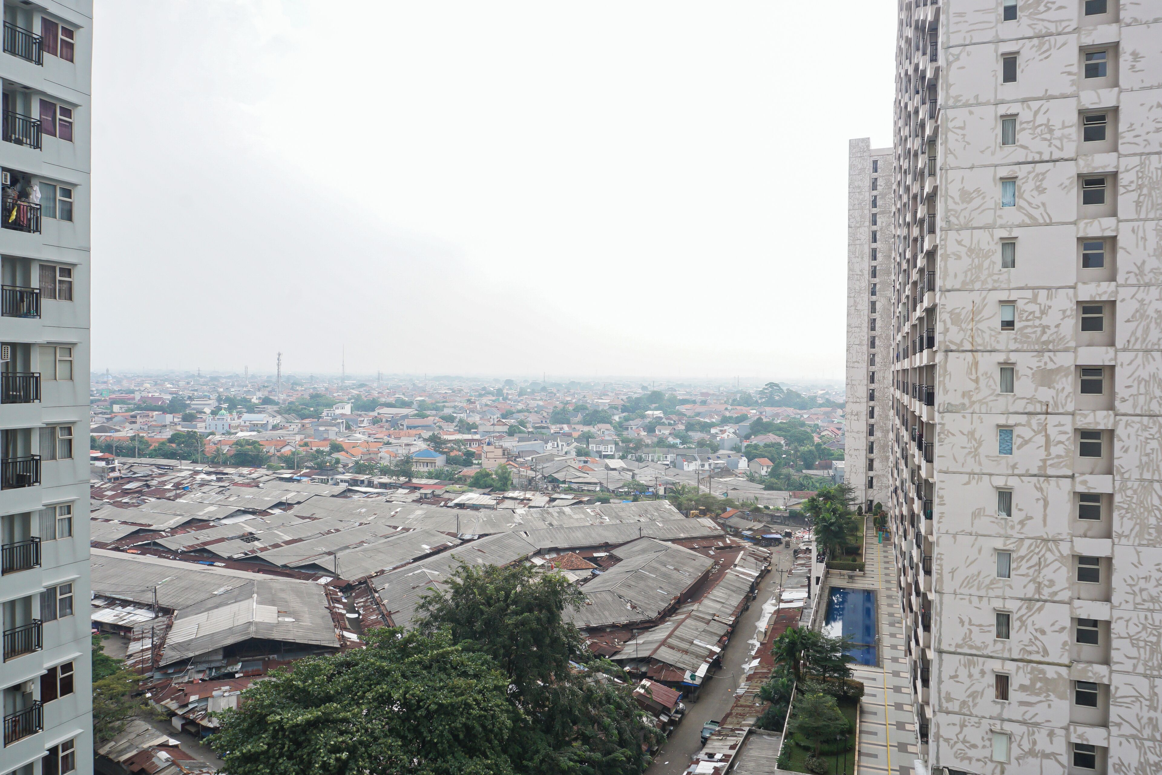 Un edificio de gran altura con múltiples balcones y vistas a una zona urbana densamente poblada, con diversos edificios e infraestructura.