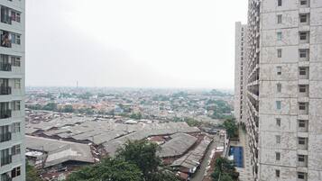 Un edificio de gran altura con múltiples balcones y vistas a una zona urbana densamente poblada, con diversos edificios e infraestructura.