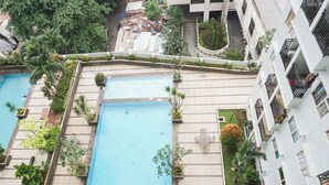A residential building with two swimming pools, surrounded by greenery and a well-maintained garden. - Compact Minimalist Studio At Apartment Margonda Residence 3 (Depok)