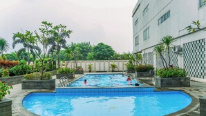 A swimming pool surrounded by planters and a building. - Compact Minimalist Studio At Apartment Margonda Residence 3 (Depok)