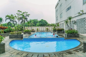 A swimming pool surrounded by planters and a building. - Compact Minimalist Studio At Apartment Margonda Residence 3 (Depok)