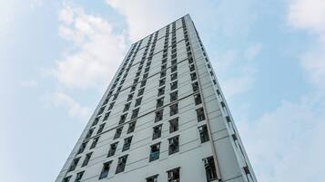 Um edifício alto e moderno, com uma fachada em grade de janelas e varandas.