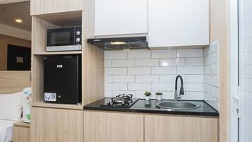 A compact kitchen with a microwave, a gas stove, and a sink.