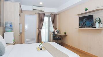 A hotel room with a bed, a desk, a TV, a water dispenser, and a window with curtains.
