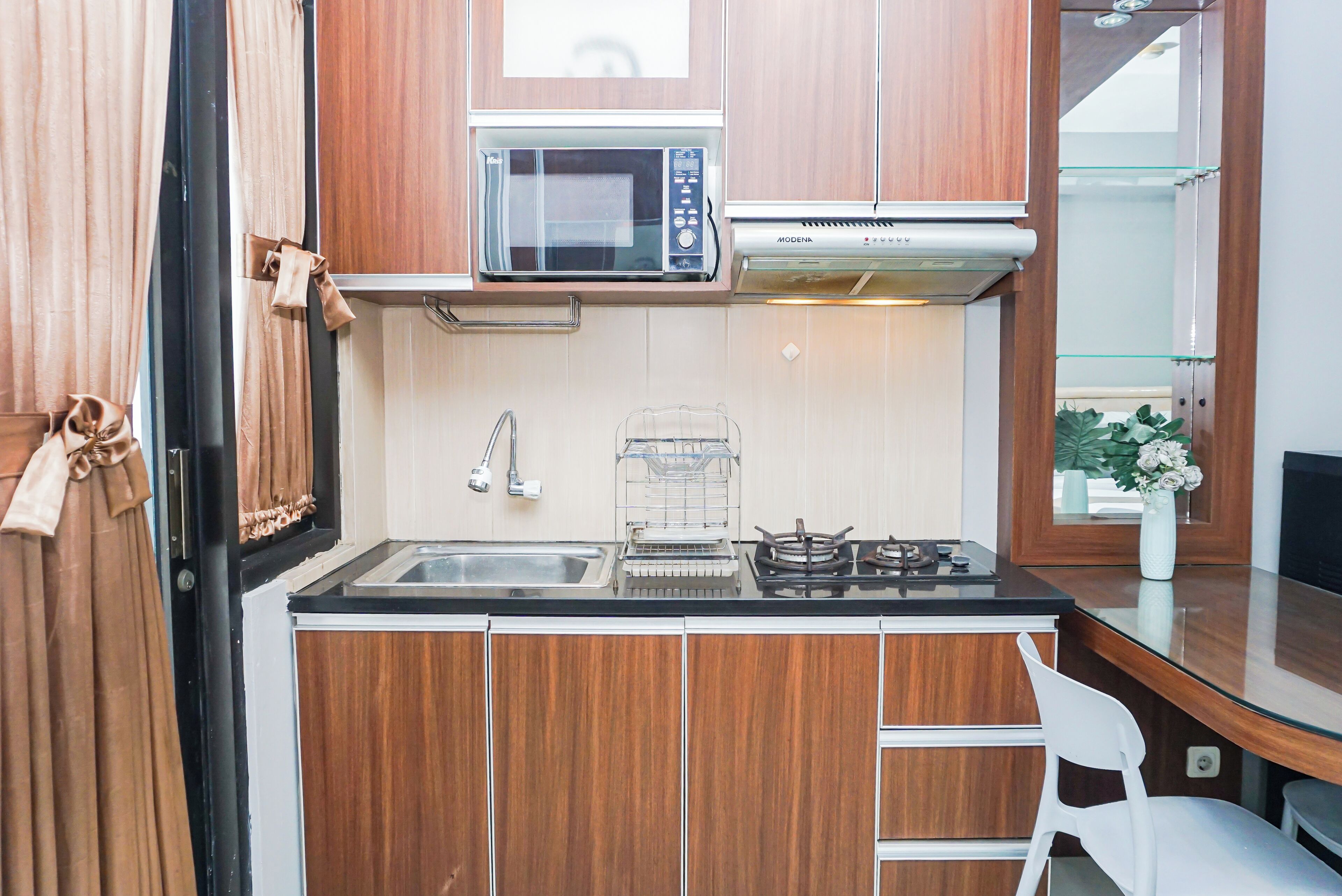A compact kitchen with a microwave, gas stove, and a small sink.