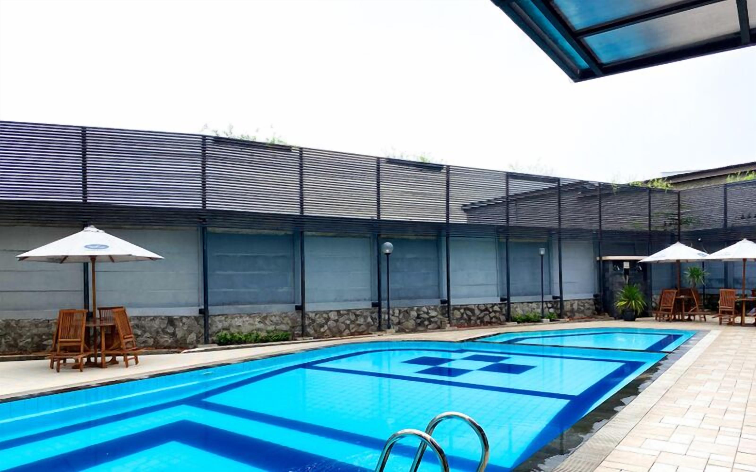 Ein Schwimmbecken im modernen Design, umgeben von Liegestühlen und Sonnenschirmen.