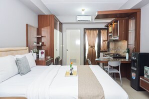 Ein Hotelzimmer mit einem Bett, einem Schreibtisch, einer Küchenzeile und einem Badezimmer.