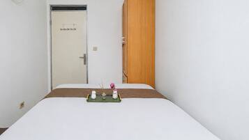 Une chambre d’hôtel avec un lit, une armoire en bois, une porte avec une poignée et une petite table agrémentée d’objets décoratifs.