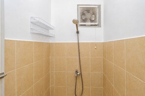 A shower area with beige tiles, a showerhead, and a wall-mounted fan. - Good Homey 2Br At Apartment Menteng Square (Jakarta)