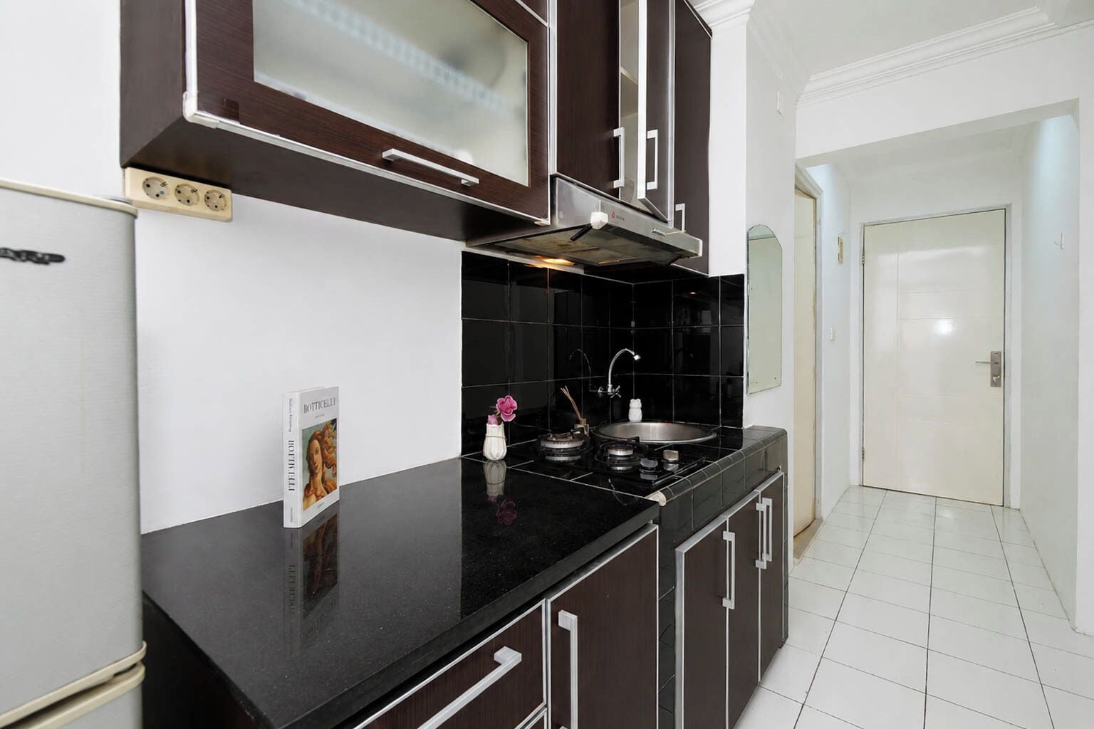 A modern kitchen with dark cabinetry, a black countertop, a stainless steel sink, and a built-in oven.