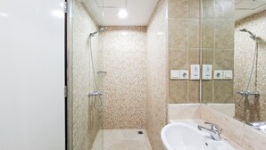A bathroom with a glass shower enclosure, a sink, and tiled walls. - Compact Look Studio (No Kitchen) At Apartment Great Western (Tangerang)