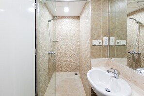 Ein Badezimmer mit Duschkabine aus Glas, Waschbecken und Fliesenwänden.