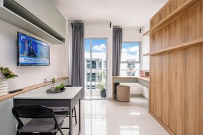 Eine moderne Küche mit Fernseher, ein Essbereich mit Tisch und Stühlen sowie ein Blick ins Freie durch große Fenster.