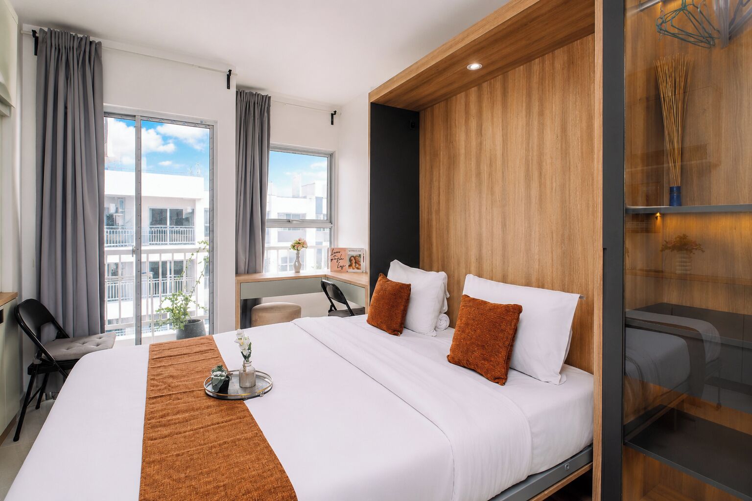 A hotel room with a large bed, a desk, a chair, and a view of the city.
