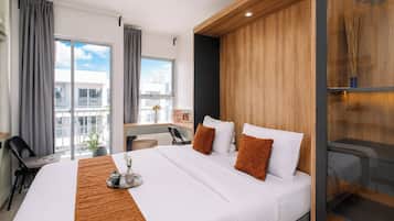 A hotel room with a large bed, a desk, a chair, and a view of the city.