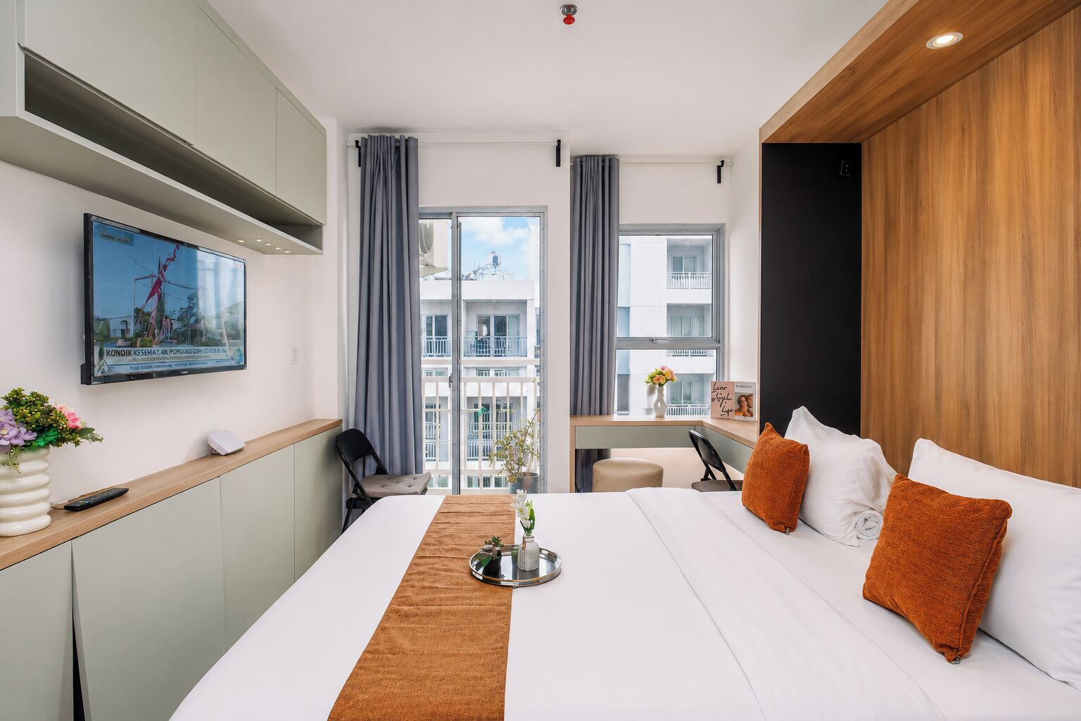 A hotel room with a bed, a desk, a TV, and a view of the outside.