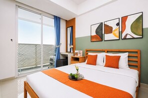 Ein Hotelzimmer mit Bett, Nachttisch, Fenster mit Vorhängen, Balkon und abstrakten Wandbildern.