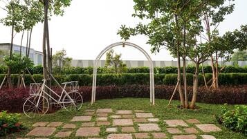 Ein Garten mit einem gepflasterten Weg, einem Fahrrad und einer weißen Bogenkonstruktion.