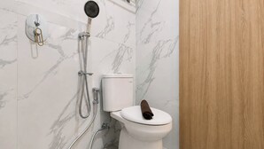 A bathroom with a toilet, a shower, and a wooden door. - Stylish And Warm Studio At Apartment The City Square Surabaya (Surabaya)