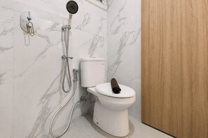 Ein Badezimmer mit Toilette, Dusche und einer Holztür.