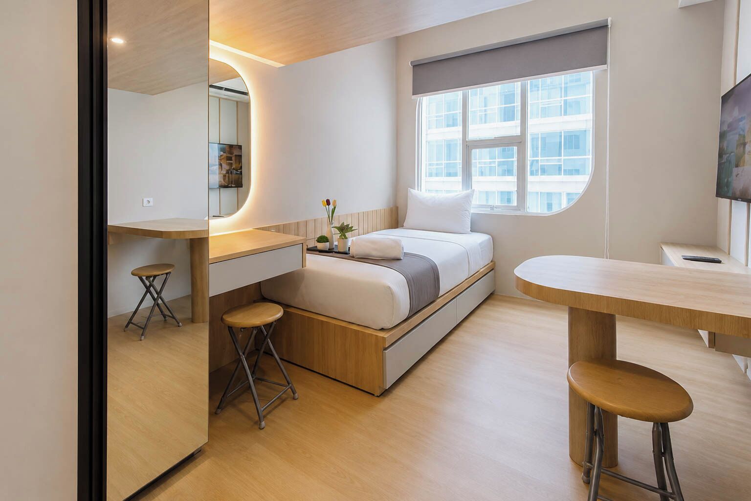 A compact bedroom with a bed, bedside table, and a small stool.