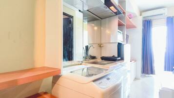 A compact kitchen with a built-in washing machine, a sink, and a microwave.