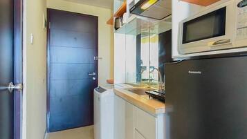 A compact kitchen with a microwave, refrigerator, and a small washing machine.