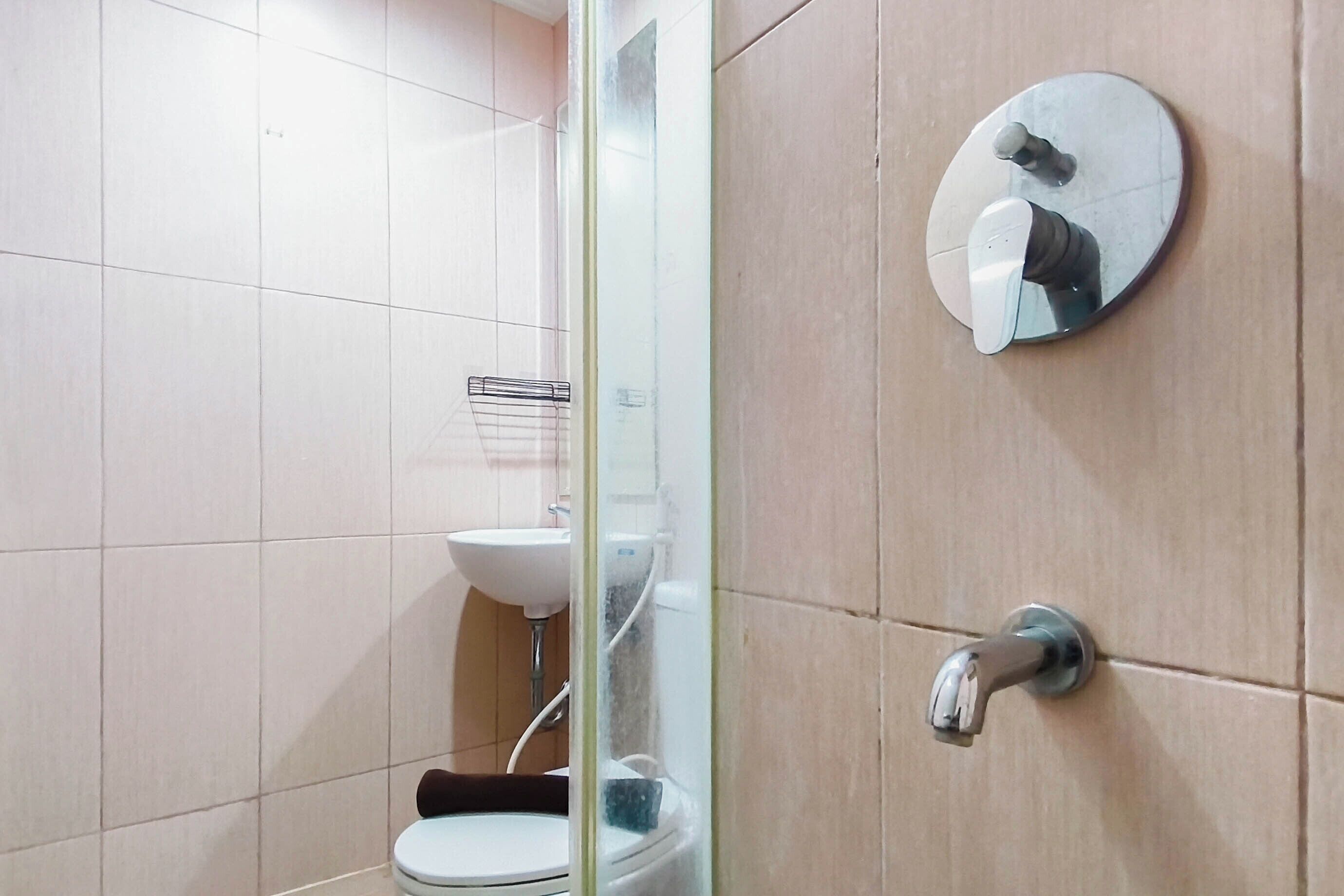 Un baño con inodoro, lavamanos y espejo con marco redondo.