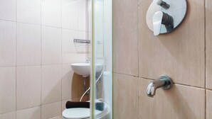 A bathroom with a toilet, sink, and a mirror with a round frame. - Urban Minimalist Studio At Apartment Tamansari Papilio (Surabaya)