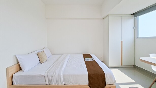 A modern bedroom with a bed, a small table, and a wardrobe. - Comfortable Nice Studio Room At Apartment Cisauk Point (Cisauk)