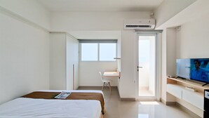 A hotel room with a bed, a desk, a television, and an air conditioning unit. - Comfortable Nice Studio Room At Apartment Cisauk Point (Cisauk)